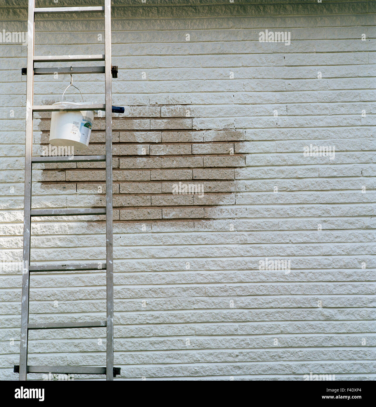 A paint can hanging on a ladder in front of an partly unpainted wall, Saltsobaden, Sweden. Stock Photo