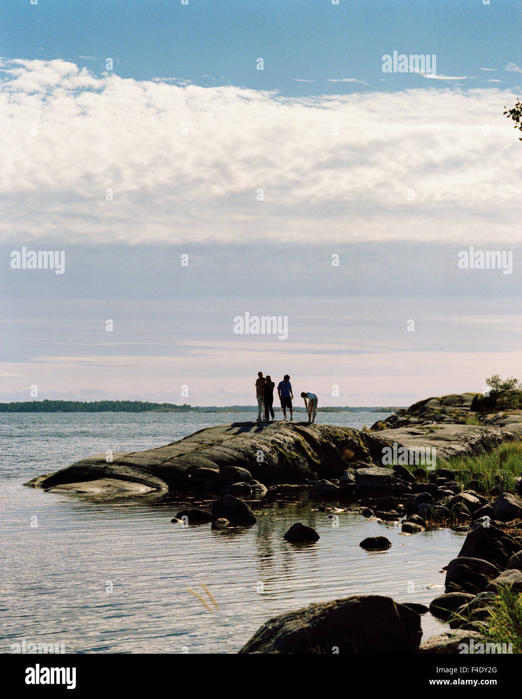 Four people standing on a bare cliff, Harstena, Gryt archipelago ...