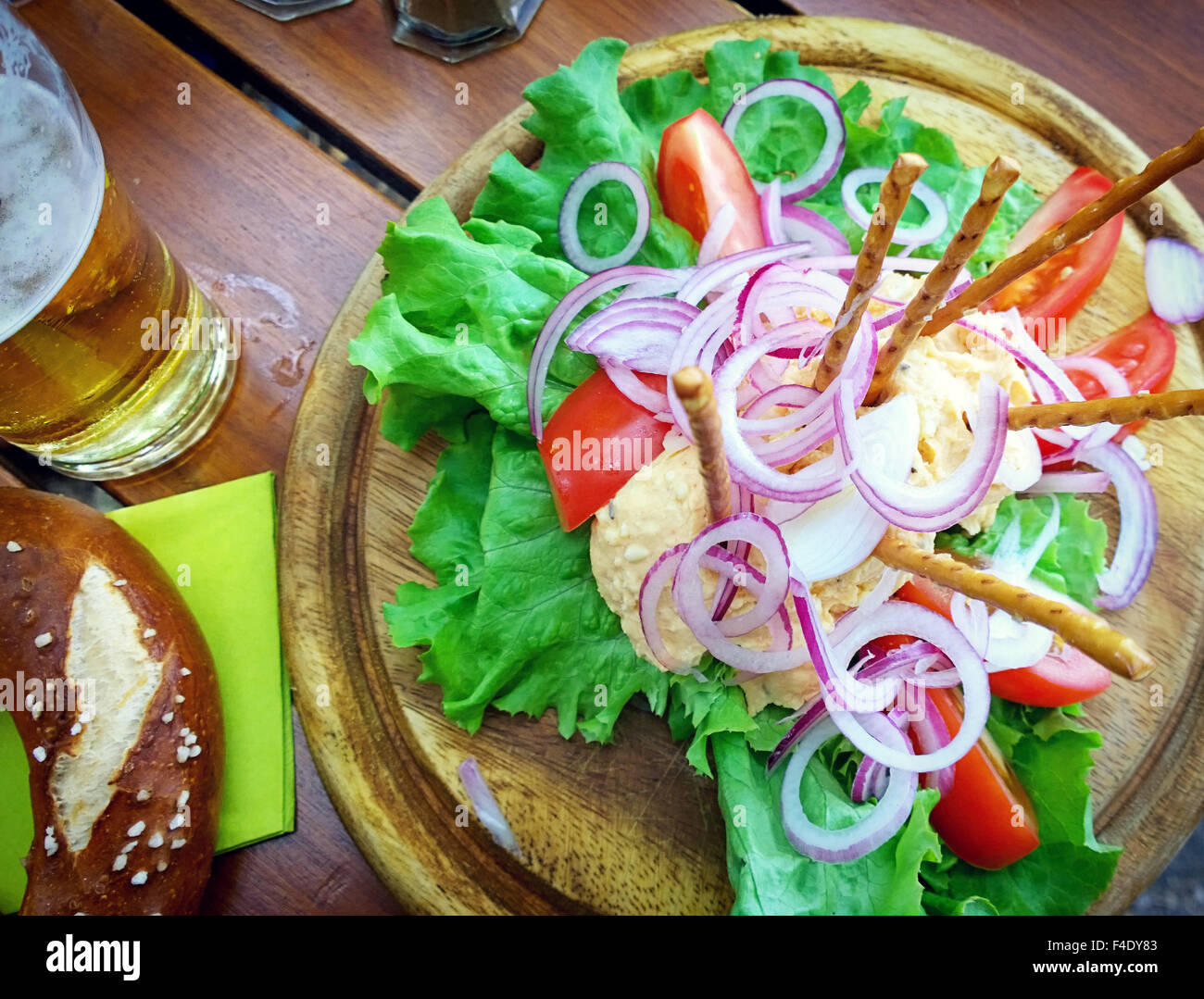 Obazda, Bavarian cheese cream specialty served with onion rings tomatoes,salad, salty sticks, pretzel and beer Stock Photo