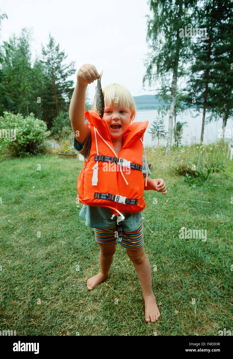 barefoot blonde capture casual clothing children only color image day  elementary age fisheries fishing girls grass happiness Stock Photo - Alamy