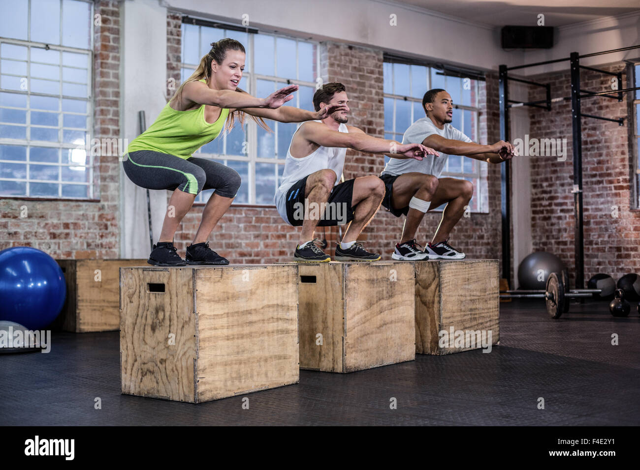 Three fit athletes squatting together Stock Photo