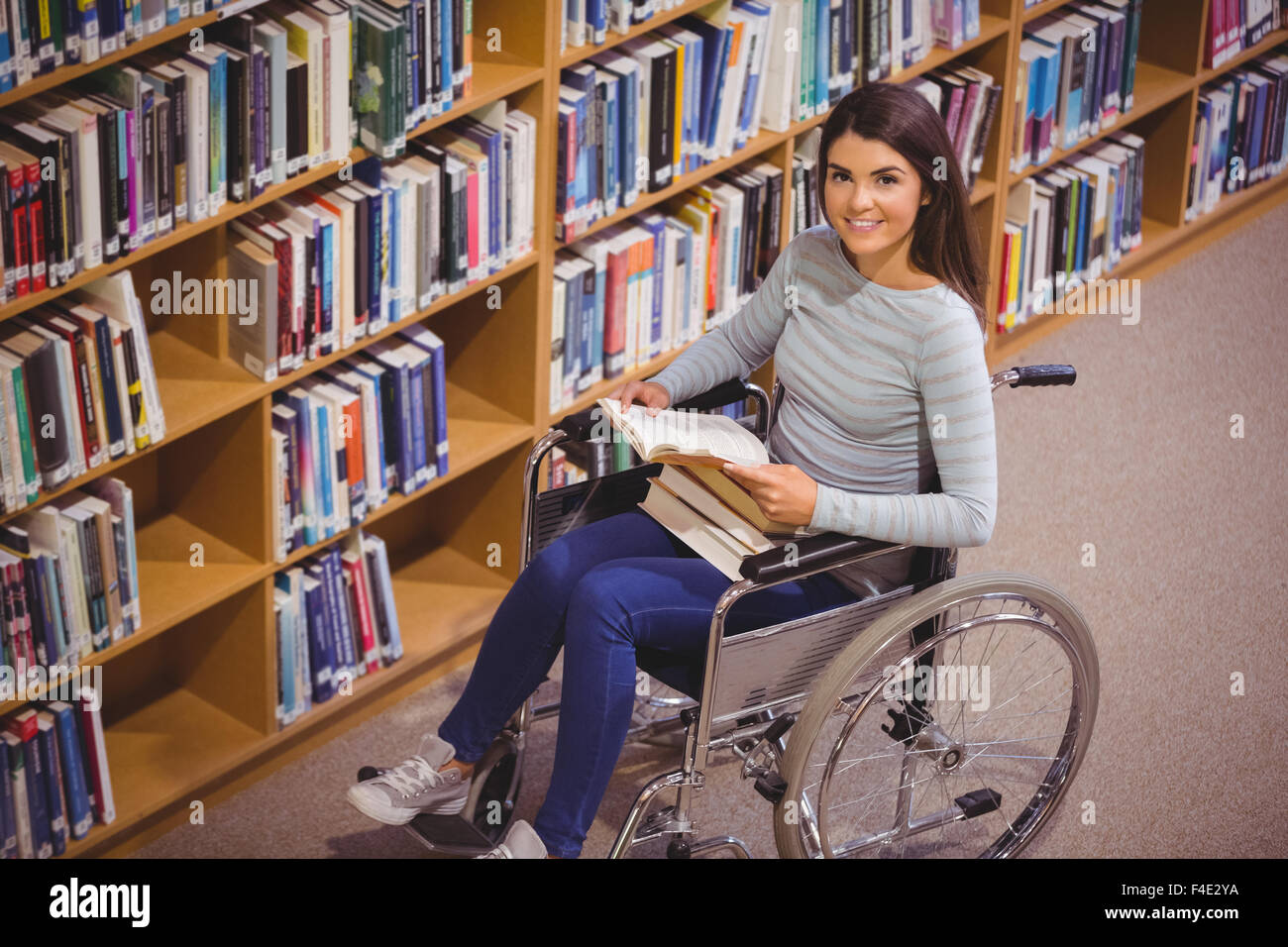 Disabled female student smiling while reading book Stock Photo