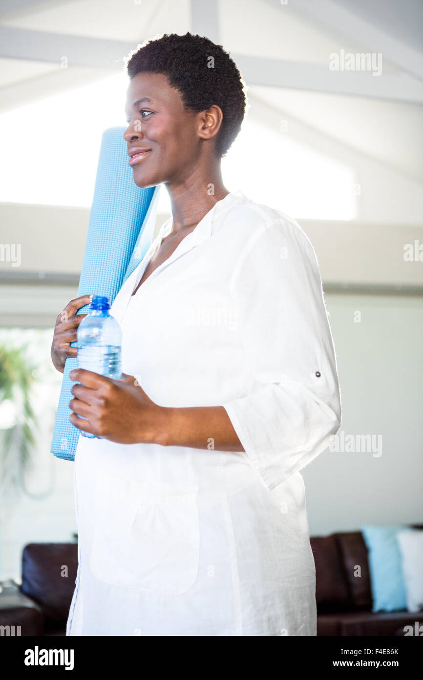 Woman holding bottle and exercise mat while standing Stock Photo