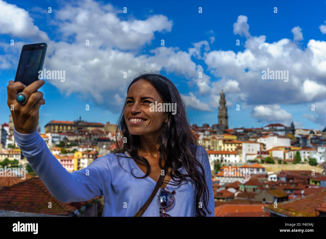 Beautiful woman takes a selfie with a smartphone with the background of old town Porto. September, 2015. Porto, Portugal. Stock Photo