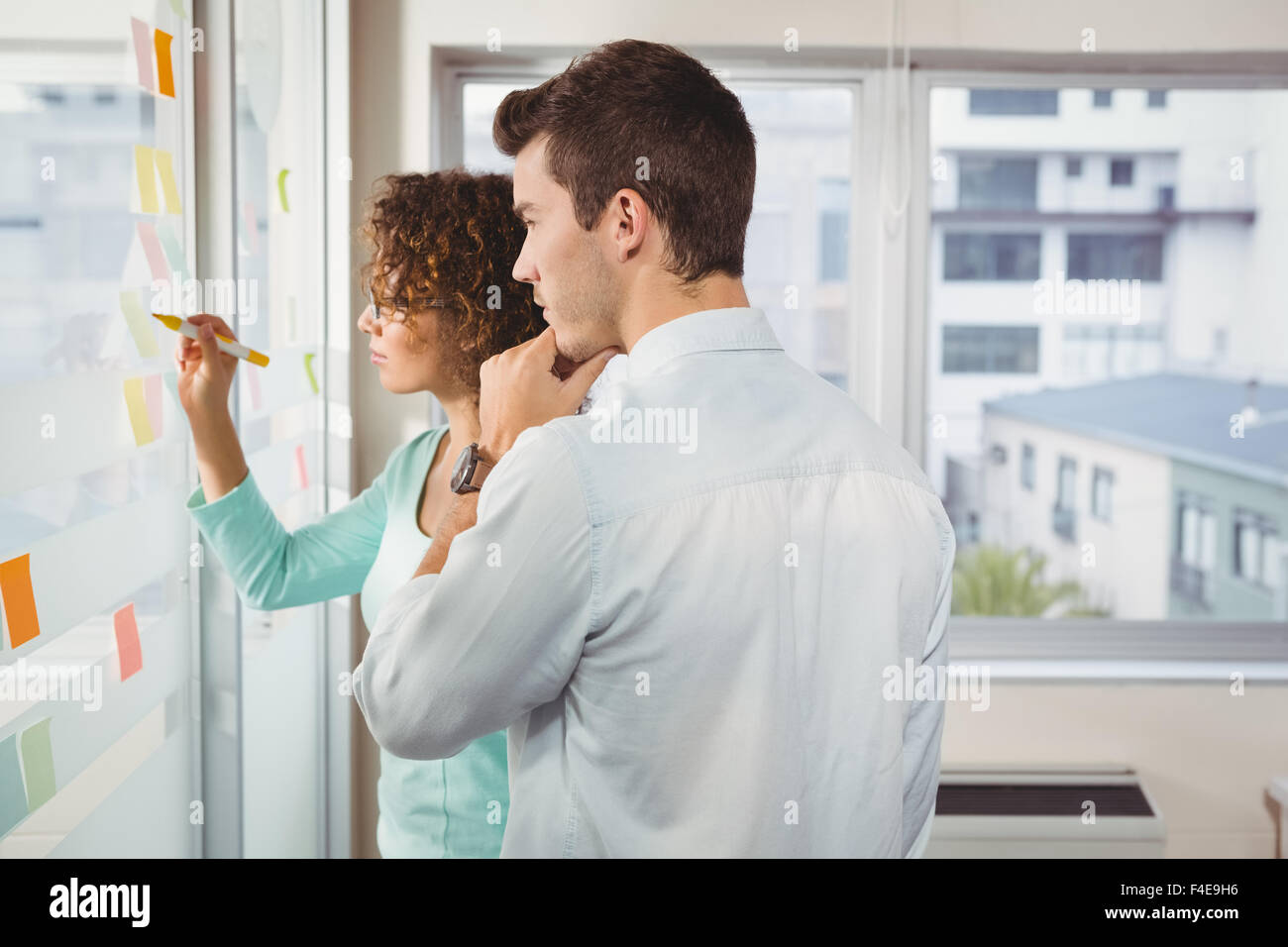 Businesswoman writing on adhesive note in creative office Stock Photo