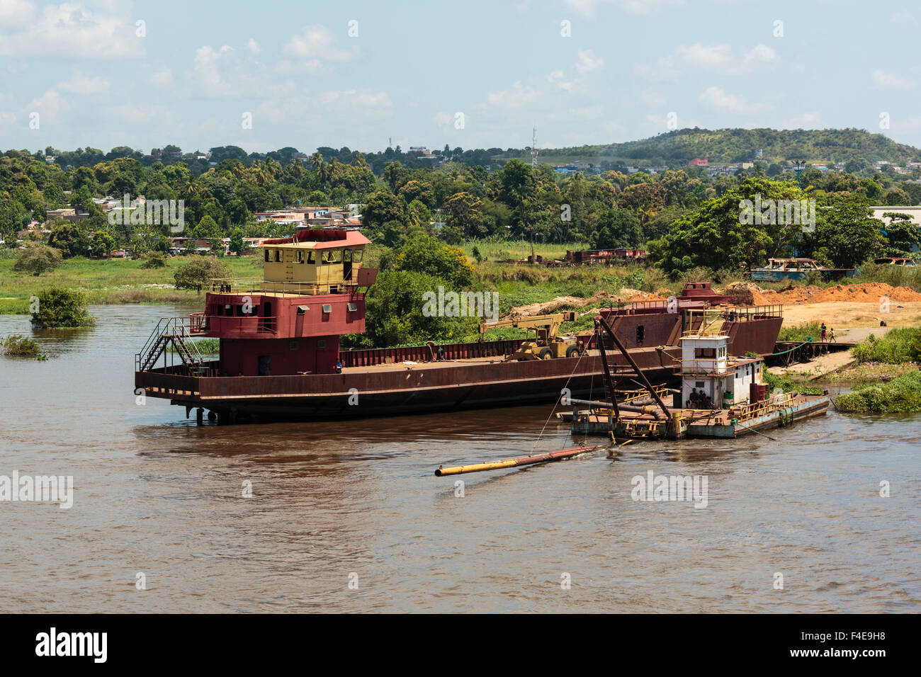 South America, Venezuela, Orinoco River. Tug and boat loading supplies on river. Stock Photo