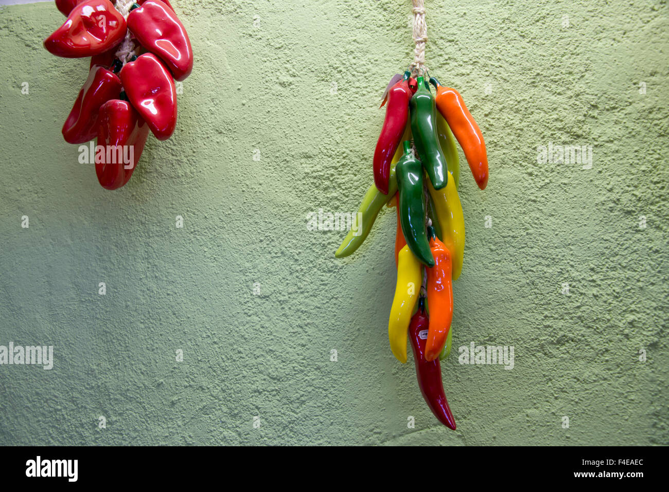Arizona, Tucson, Tubac. Hanging ceramic chili peppers on green adobe
