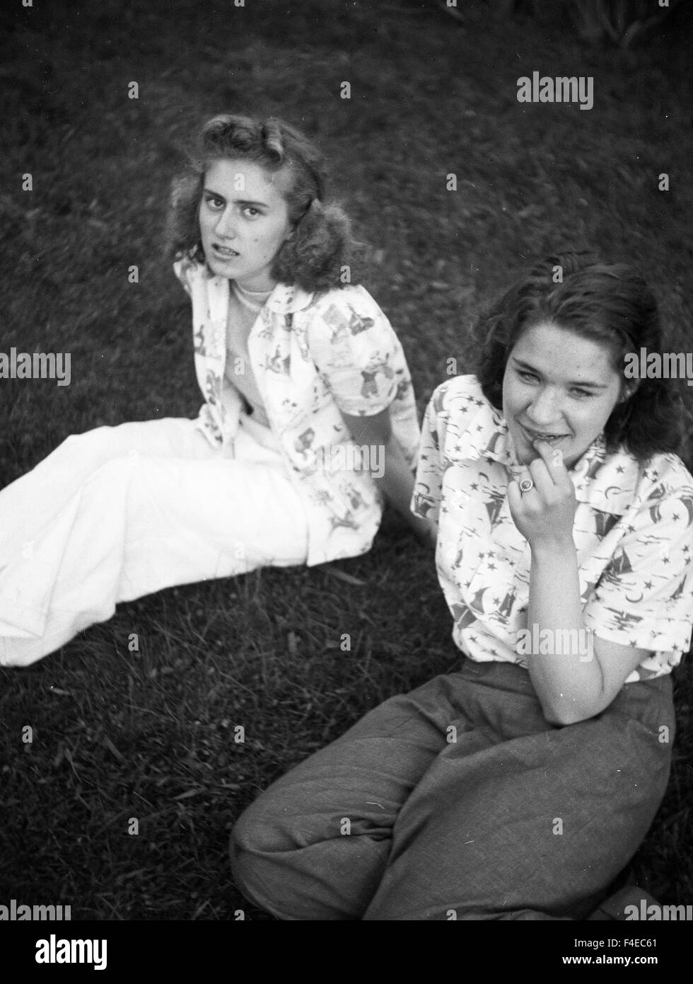 fashionable teenage girls sitting on grass during the 1940s Stock Photo