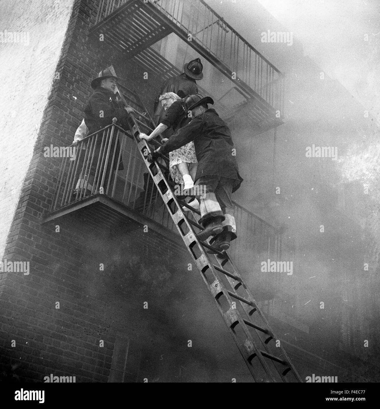 Firefighters rescue and elderly woman from an apartment fire during the 1950s Stock Photo