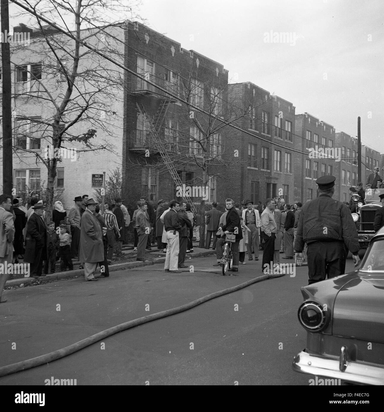 Overall scene of an apartment building with people standing in the street watching during a fire Stock Photo