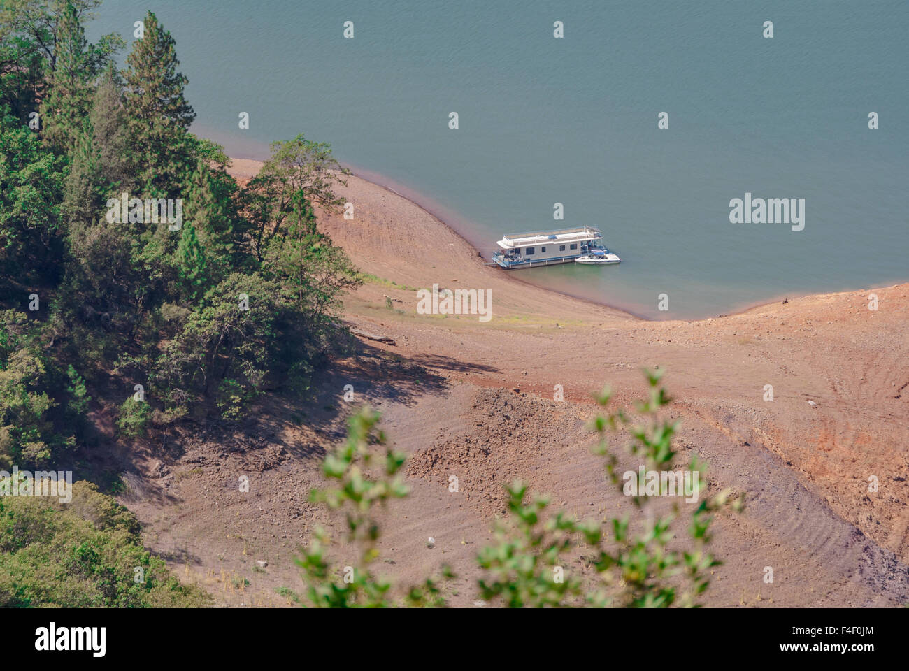 Houseboat parked in cove on Lake Shasta during drought in California while wild fires were burning at Mount Shasta. Stock Photo