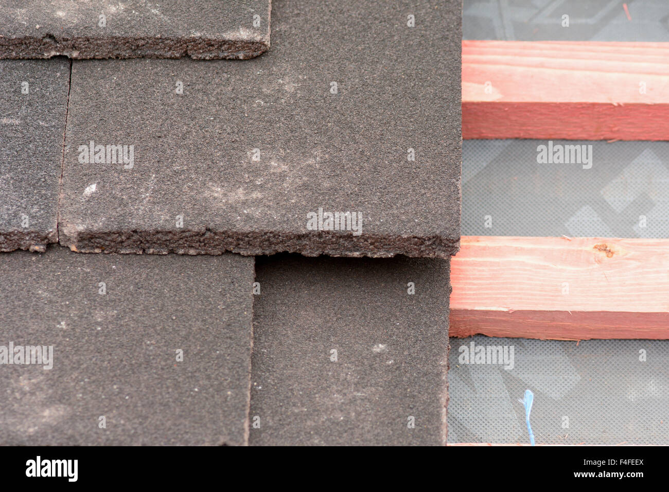 Rows of roof tiles being fitted to wooden battens on Victorian style