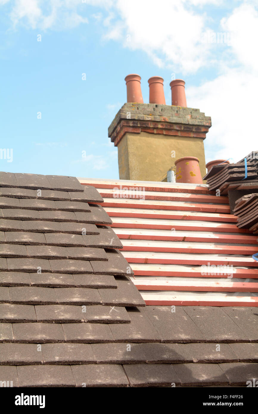 Roofer fixing tiles to wooden battens on roof of Victorian style
