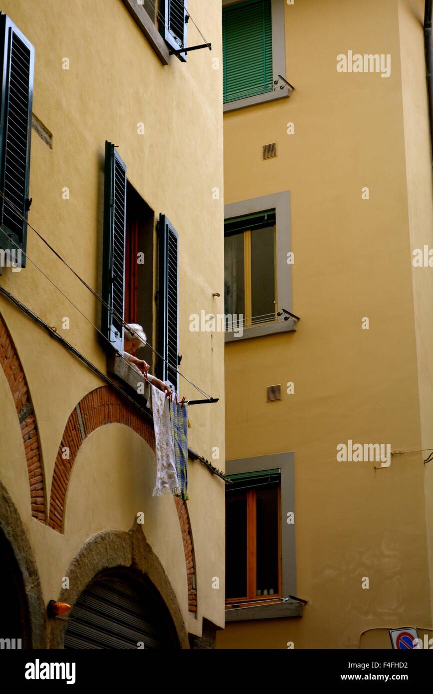 Woman hanging out laundry from her window in Florence, Italy Stock