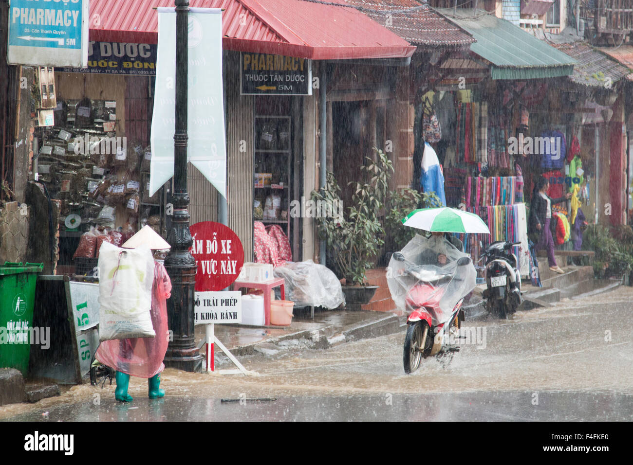 Sapa or Sa Pa is a frontier town in north west Vietnam, shots here in the rainy wet season as rider carries umbrella on scooter Stock Photo
