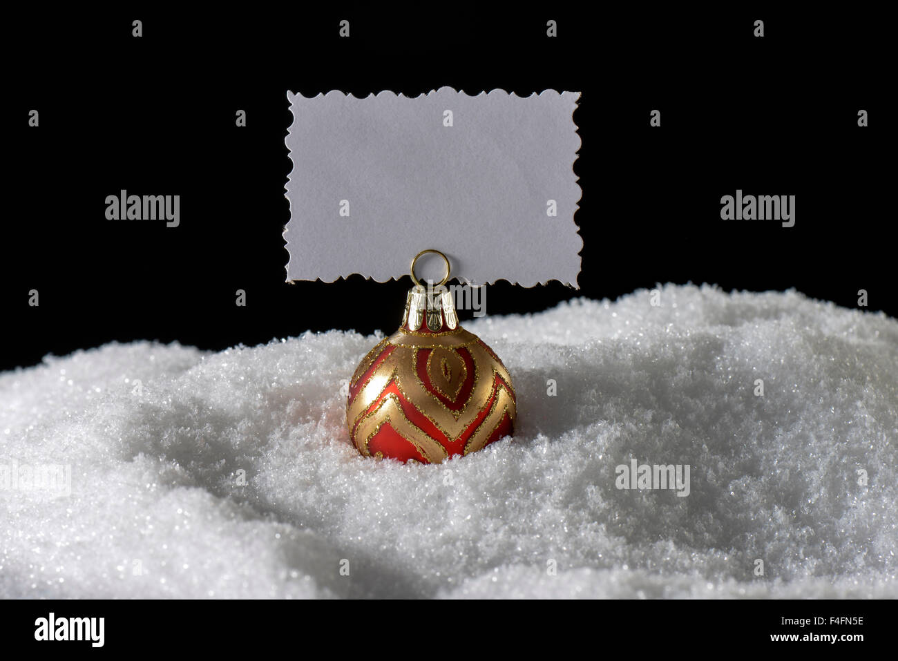 Christmas ball with greeting card blank on snow Stock Photo