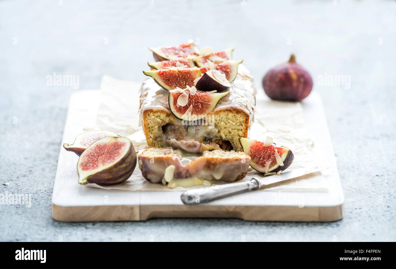 Loaf cake with figs, almond and white chocolate on white serving board over grunge background, selective focus Stock Photo