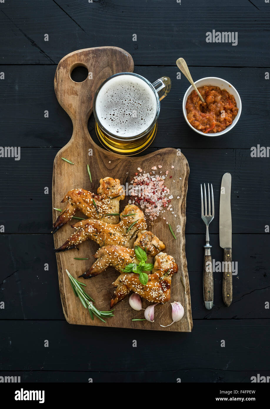 Fried chicken wings on rustic serving board, spicy tomato sauce, herbs