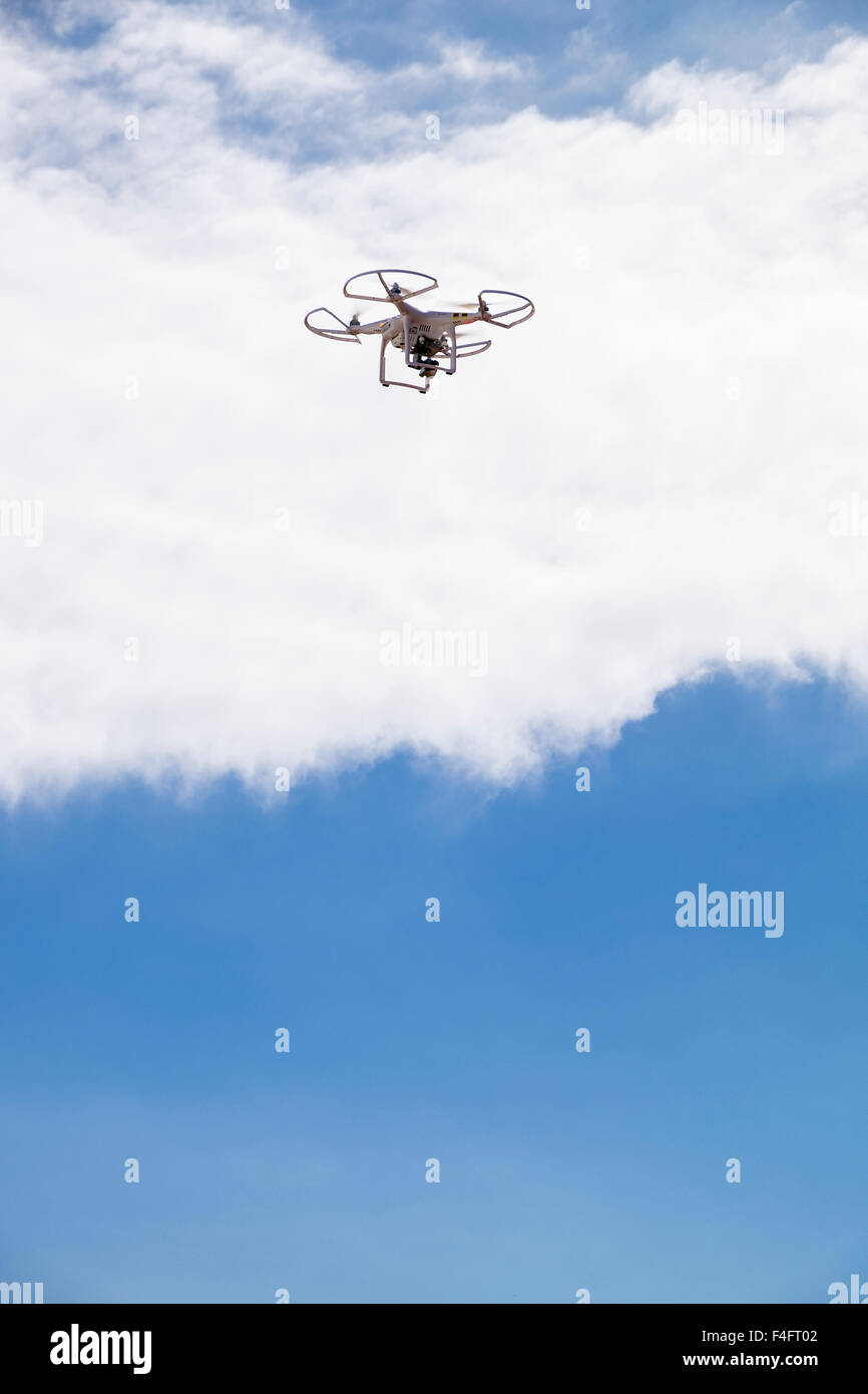 Phantom drone flying above against white cloud in blue sky with gopro video camera. Stock Photo