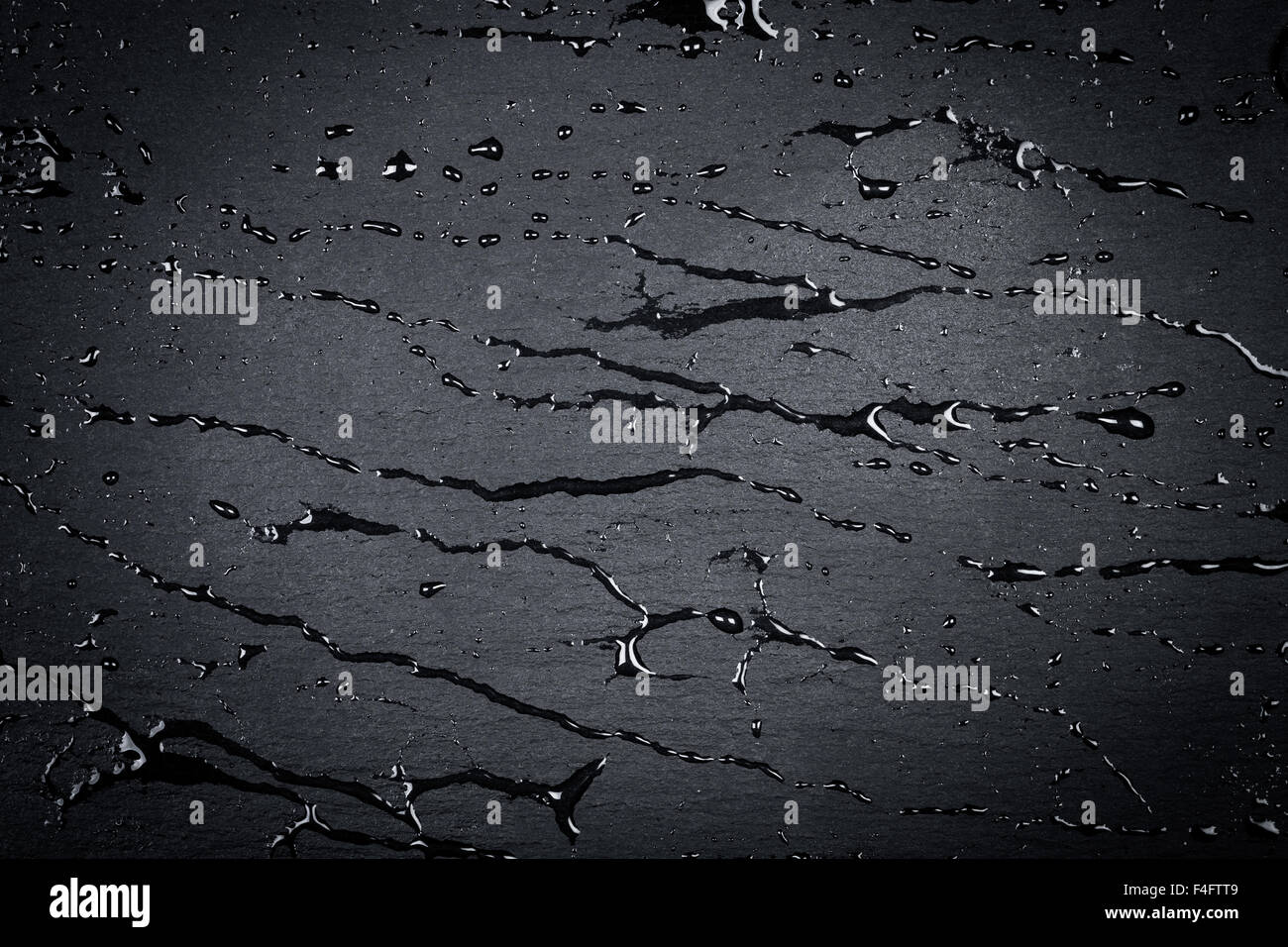 Water drops on dark stone surface of basalt or granite Stock Photo