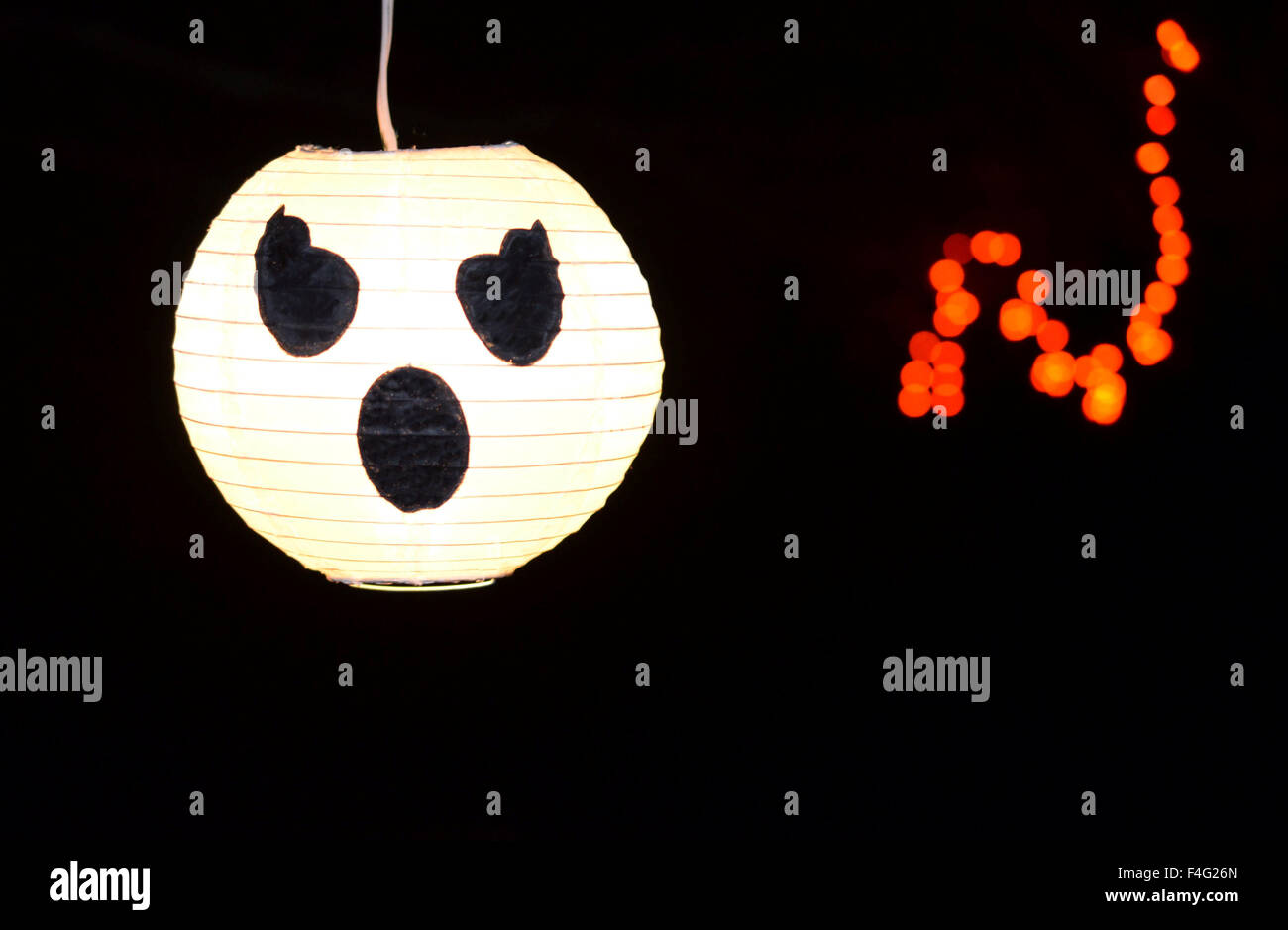 White glowing ghost pumpkin face.  Halloween decor in the night.  Includes glowing orange accent. Stock Photo