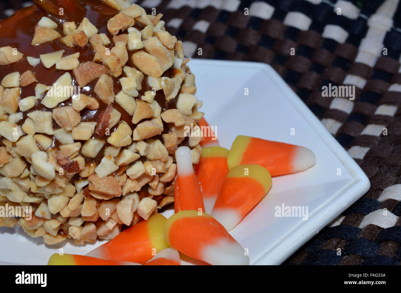 Macro of caramel apple covered with nuts and served with candy corn Stock Photo