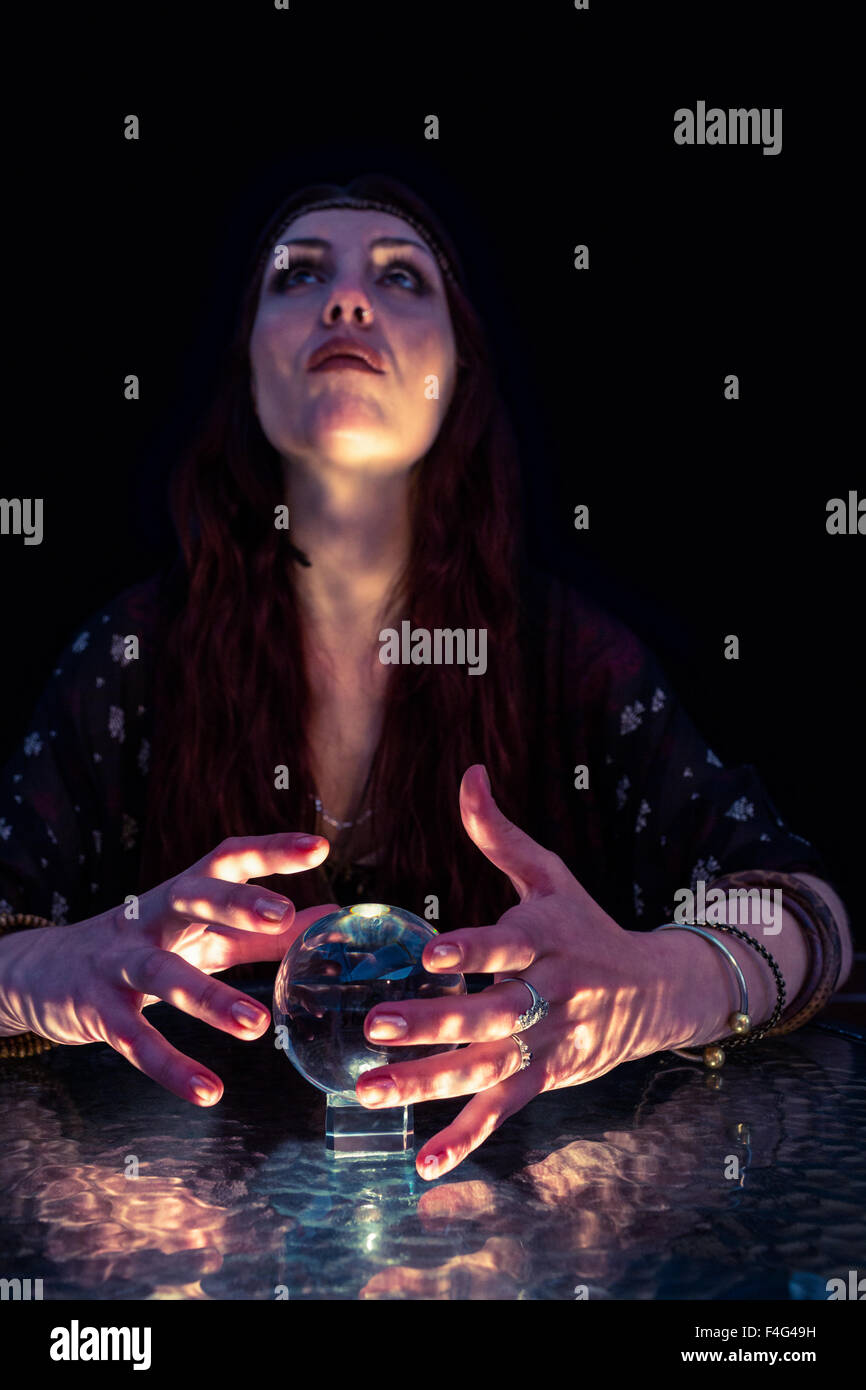 Fortune teller woman looking up and using crystal ball Stock Photo