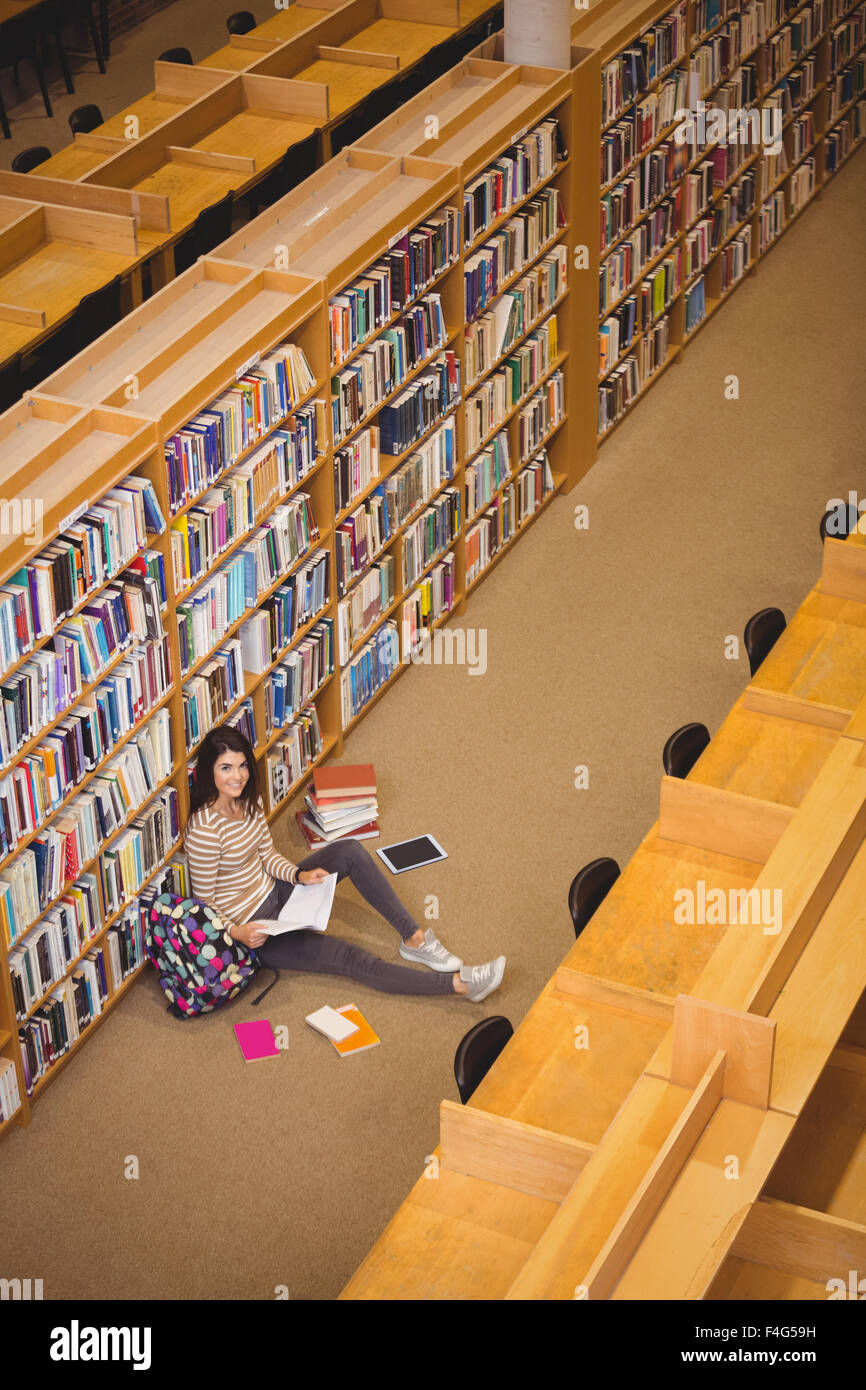 High angle portrait view of student sitting against bookcase Stock Photo