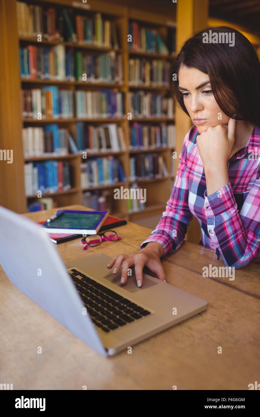 Concentrated female student using laptop at table Stock Photo