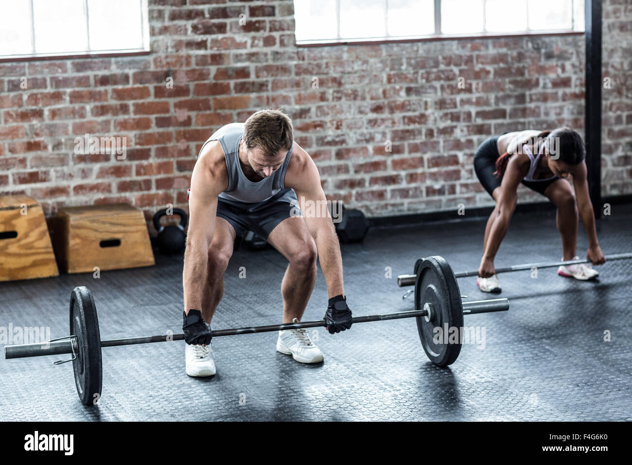 Muscular couple lifting weight together Stock Photo