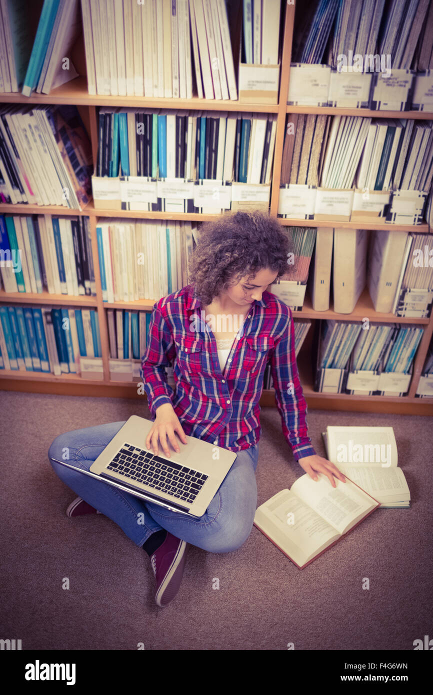 Pretty student in library using laptop Stock Photo - Alamy