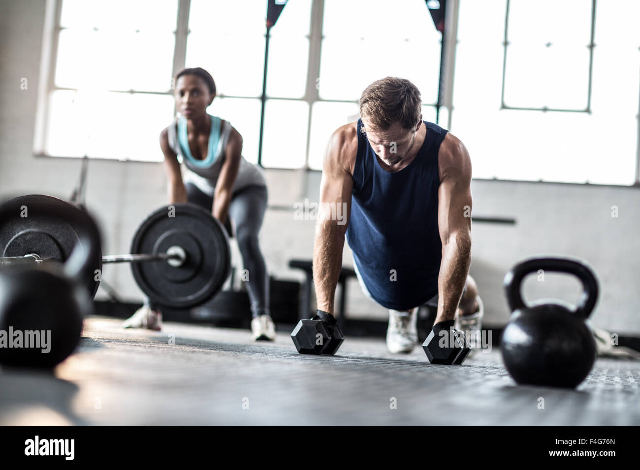 Fit couple exercising with dumbbells and barbell Stock Photo