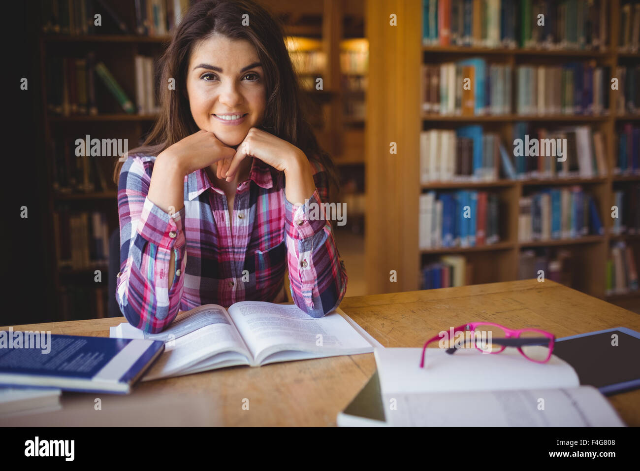Confident female student with book at table Stock Photo