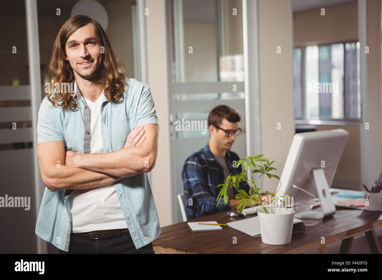 Businessman with arms crossed standing in office Stock Photo - Alamy
