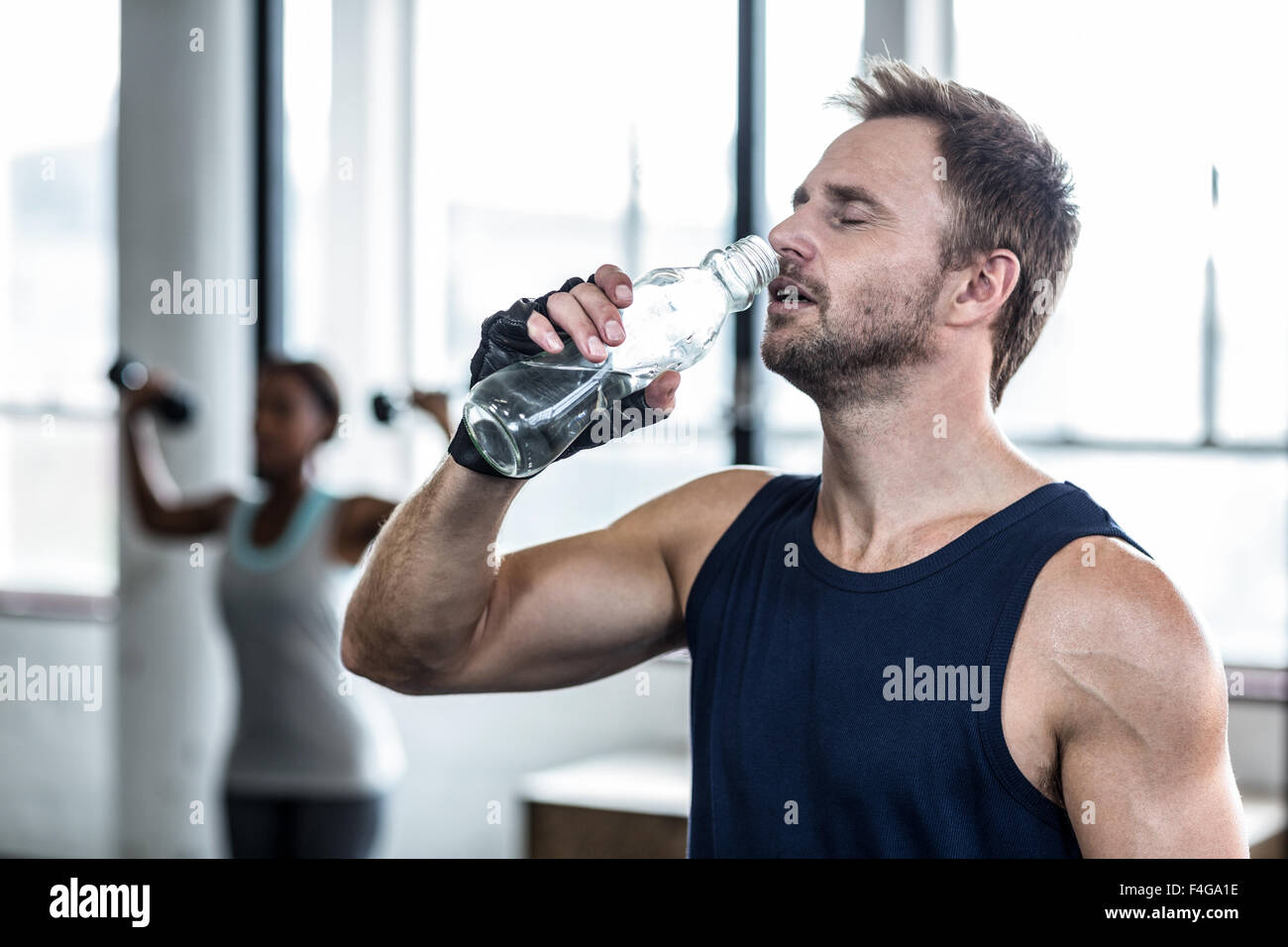 Young Bodybuilder drinking a bottle of water after the training Stock Photo
