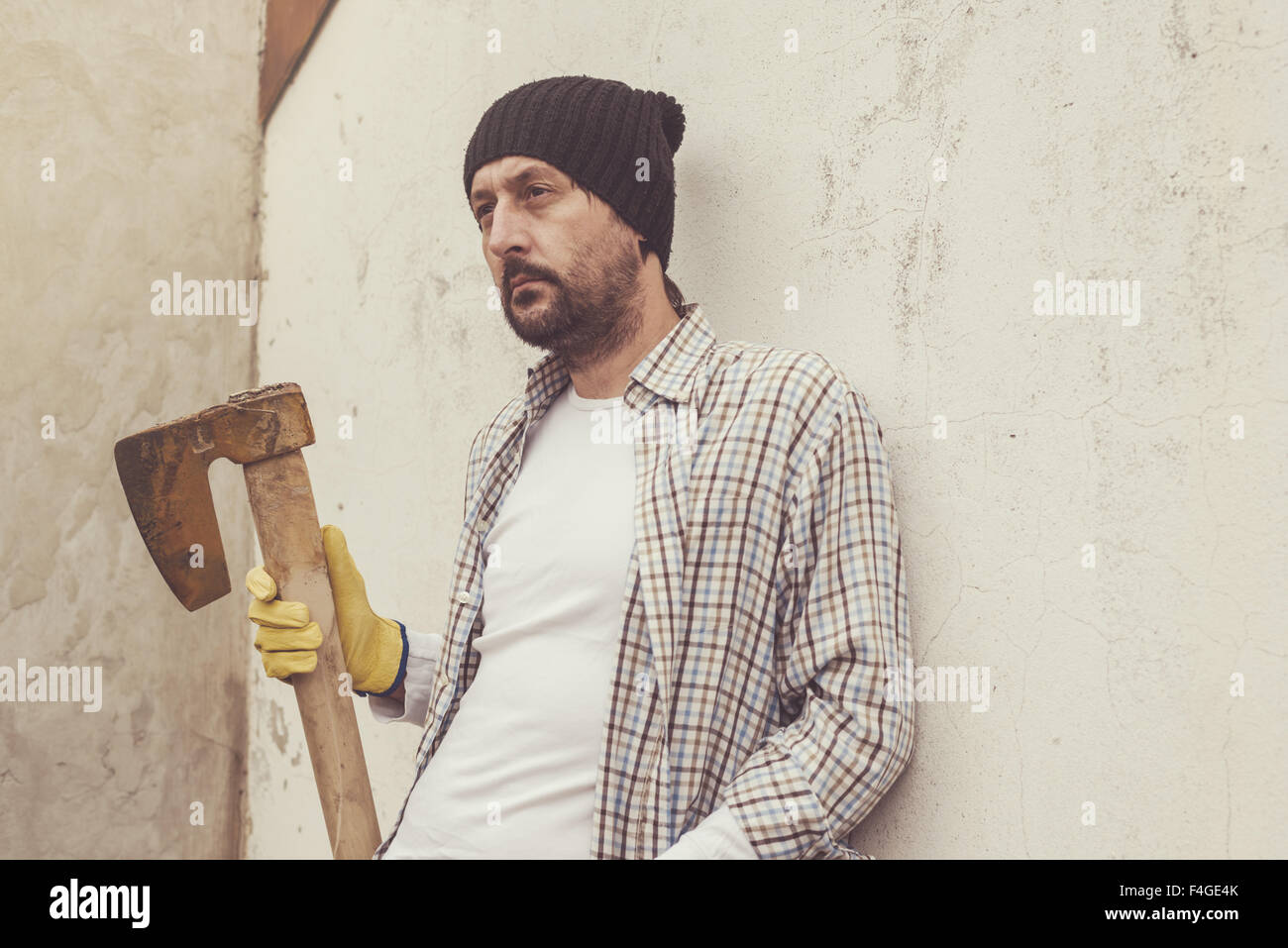 Serious confident lumberjack, adult bearded man holding a big axe in outdoors surrounding Stock Photo
