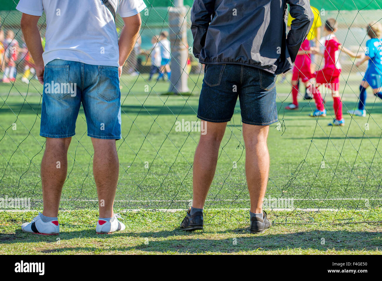 Fathers watching their sons playing soccer game, kids playing football, selective focus Stock Photo