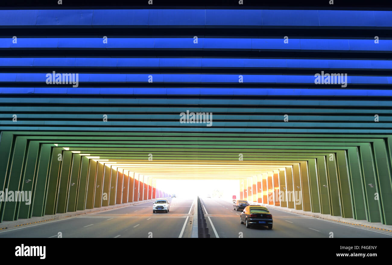 Beijing, China. 13th Oct, 2015. Cars run into a rainbow-like tunnel near an intersection of Zhengzhou-Kaifeng highway and S223 provincial road in central China's Henan Province, Oct. 13, 2015. More than 80 U-shape box girders in 12 gradients colors are installed on both ends of the tunnel. The rainbow-like tunnel could relieve the visual fatigue of drivers. © Zhu Xiang/Xinhua/Alamy Live News Stock Photo