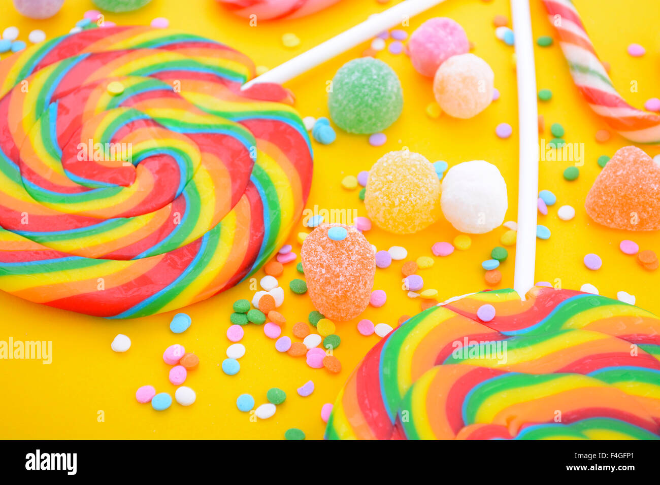 Bright rainbow lollipop candy on colorful yellow wood table for Halloween Trick or Treat or Childrens Party. Stock Photo