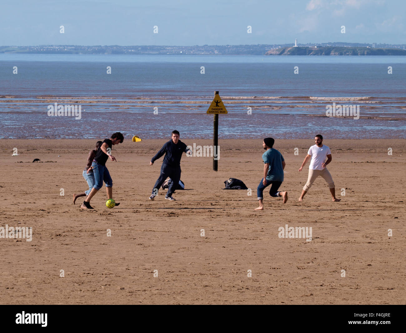 Multi-racial group of young men playing football on the beach, Weston-super-Mare, Somerset, UK Stock Photo