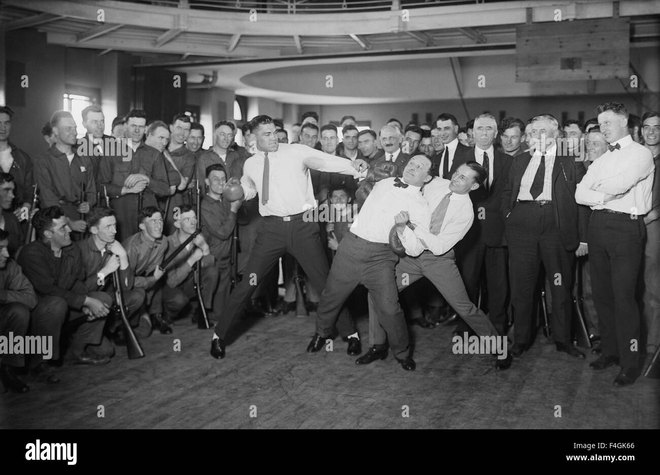 JACK DEMPSEY American boxer at left 'spars' with illusionist Harry Houdini who is held up by champion lightweight  boxer Benny Leonard. Photo Bain News service about 1920 Stock Photo