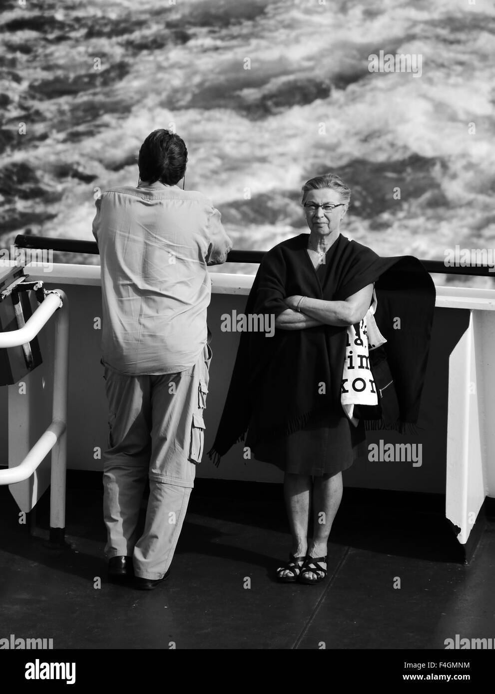 A man and a woman at the back of a boat, facing away from each other, in black and white Stock Photo