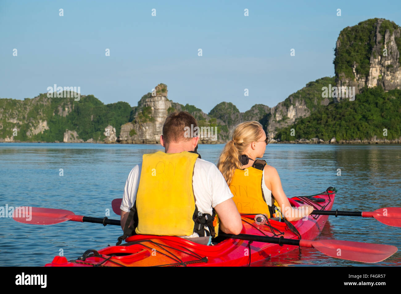 tourists paddle in kayaks in the waters of Cang Do, part of Ha long bay in north east vietnam, unesco world heritage location Stock Photo