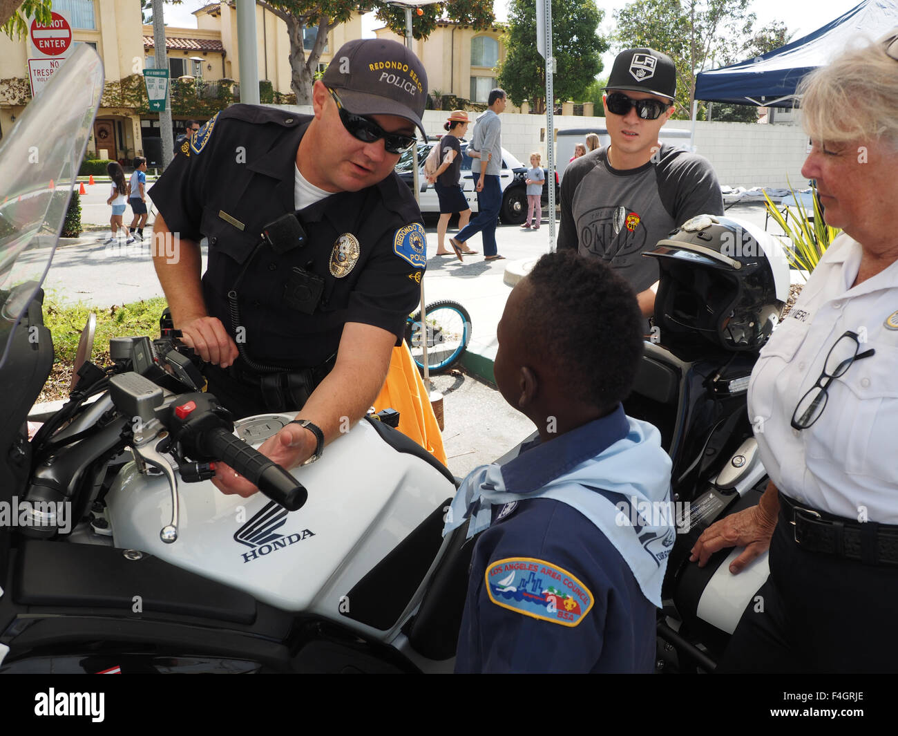 Motorcycle policeman explains Honda motorcycle to black boy scout. Redondo Beach CA. Stock Photo