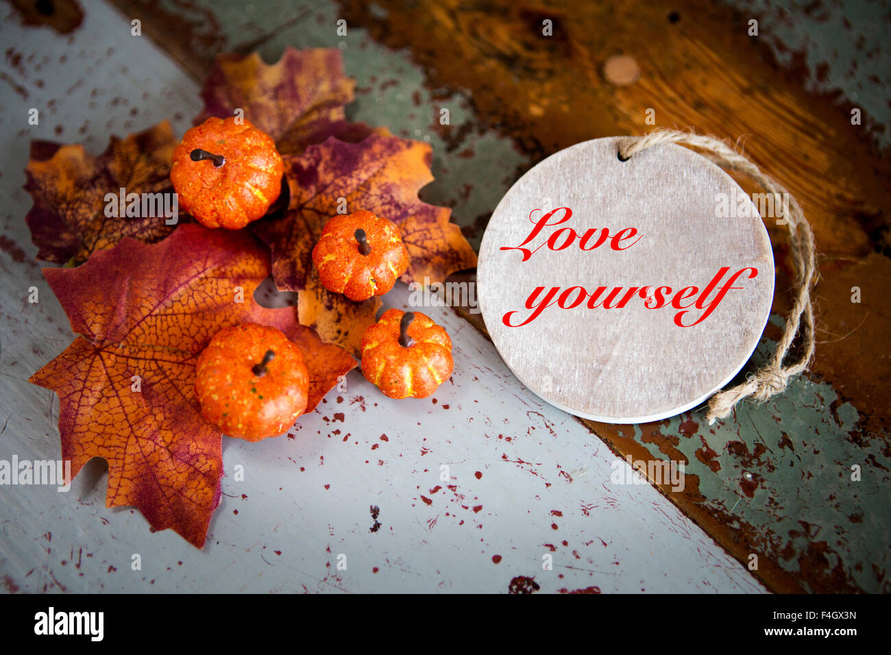 'Love Yourself' on wooden tag on old vintage table with pumpkins and leaves Stock Photo
