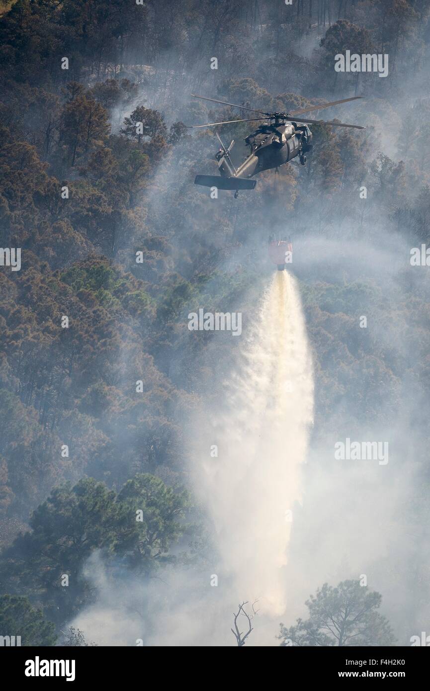 A Texas Army National Guard UH-60 Black Hawk helicopter drops water on the Hidden Pines Fire October 14, 2015 near Bastrop, Texas. Stock Photo