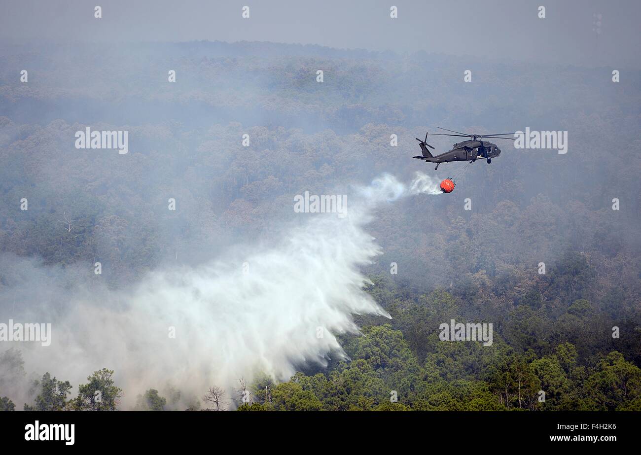 A Texas Army National Guard UH-60 Black Hawk helicopter drops water on the Hidden Pines Fire October 15, 2015 near Bastrop, Texas. Stock Photo