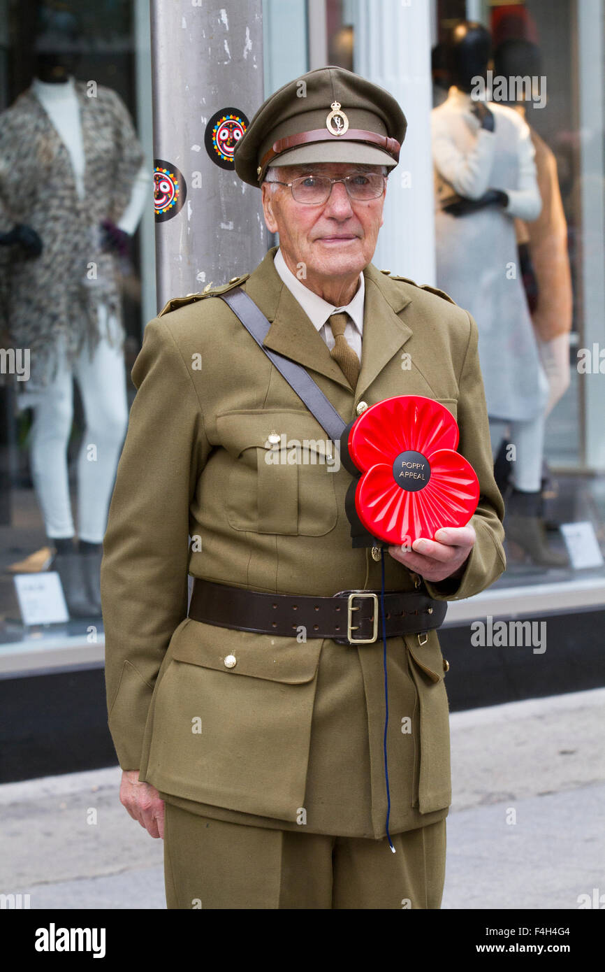 Ex-Army veteran holding large plastic poppy, UK uniformed military personnel 'Lest we Forget' collecting on the streets of Liverpool, Merseyside, UK Stock Photo