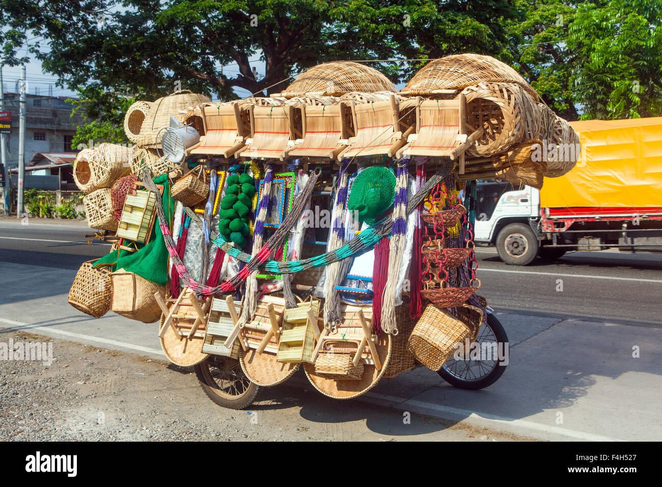 Filipino sells woven rattan baskets and other household items on the side of a road from his heavily loaded motorcycle. Stock Photo