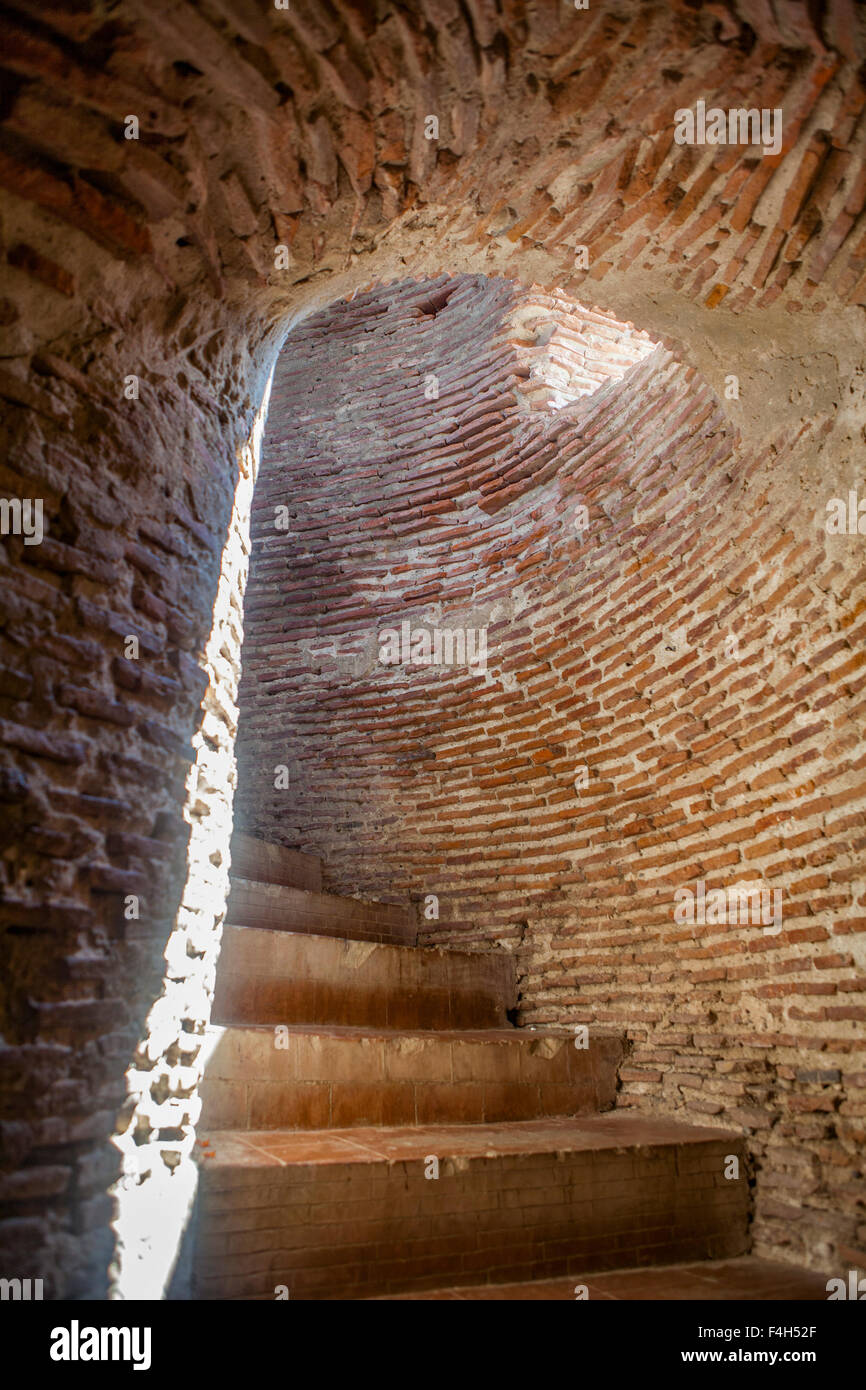 Red brick steps spiral upward inside the Bell Tower of Bantay, ruins of a Spanish church in the Philippines. Stock Photo